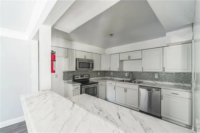 a kitchen with stainless steel appliances kitchen island granite countertop a sink stove and refrigerator