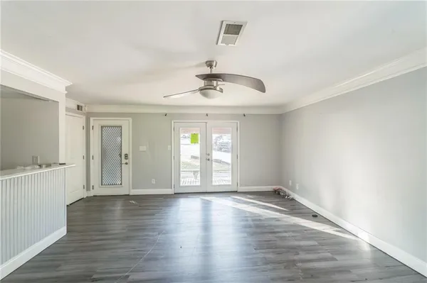 a view of an empty room with wooden floor and a window