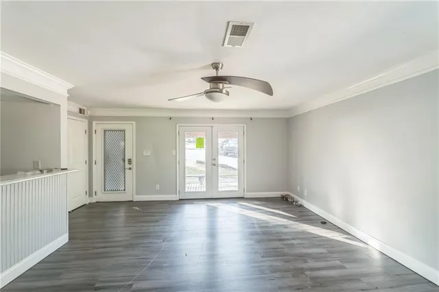 a view of an empty room with wooden floor and a window