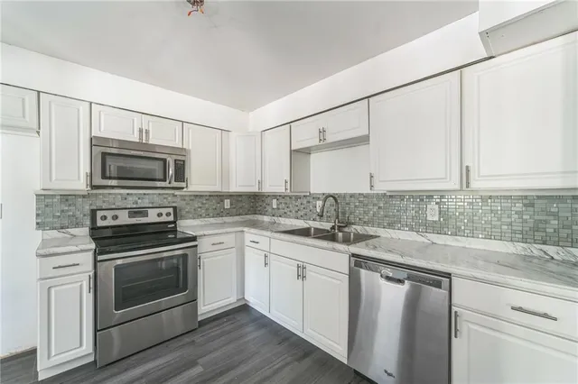 a kitchen with granite countertop white cabinets stainless steel appliances and a sink