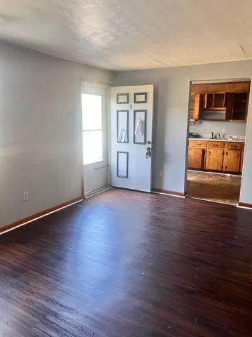 a view of an empty room with window and wooden floor