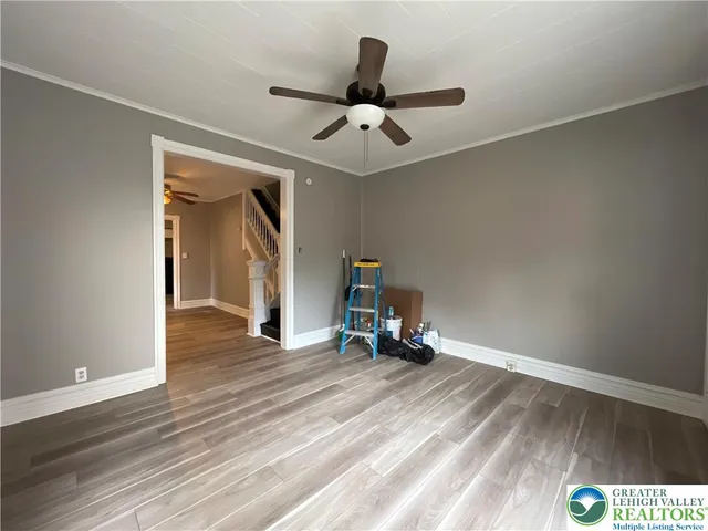 an empty room with wooden floor and ceiling fan