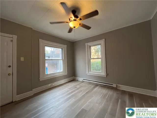 a view of an empty room with wooden floor and a window