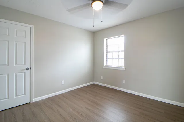 an empty room with wooden floor and ceiling fan