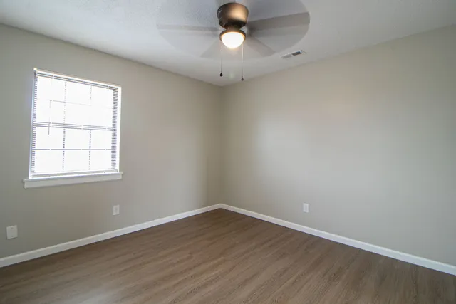 a view of a brick house with a big yard and large tree