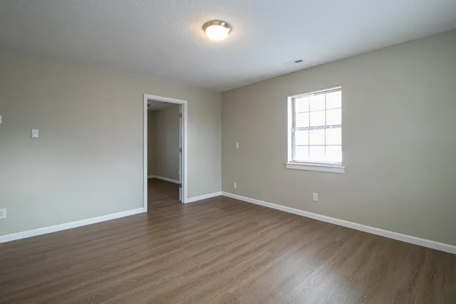an empty room with wooden floor and mirror