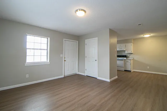 an empty room with wooden floor and windows