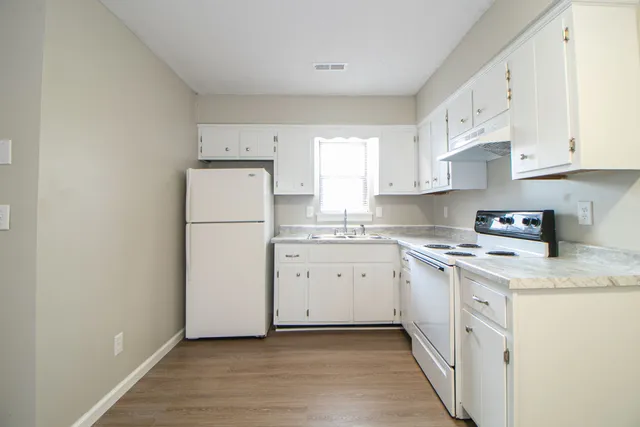 an empty room with wooden floor mirror and windows