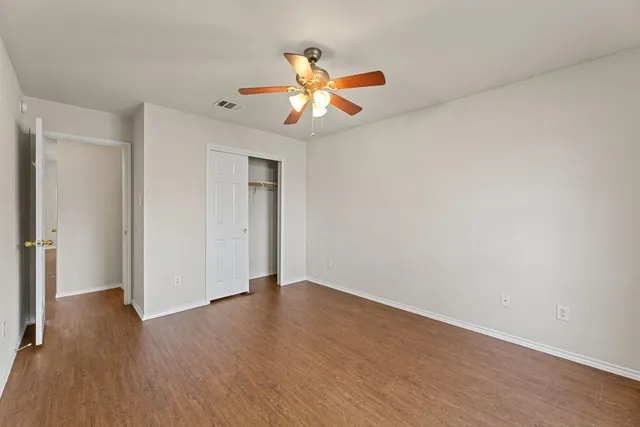 an empty room with wooden floor closet and windows