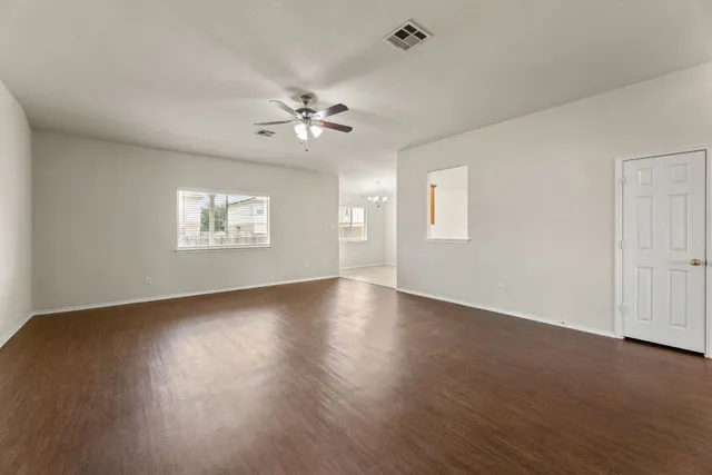 a view of an empty room with a window and wooden floor
