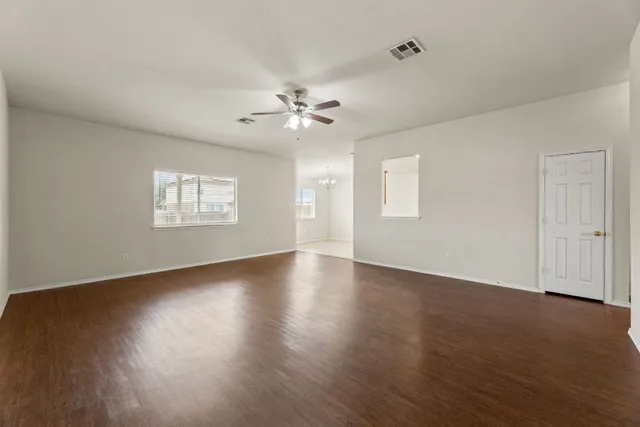 a view of an empty room with a window and wooden floor