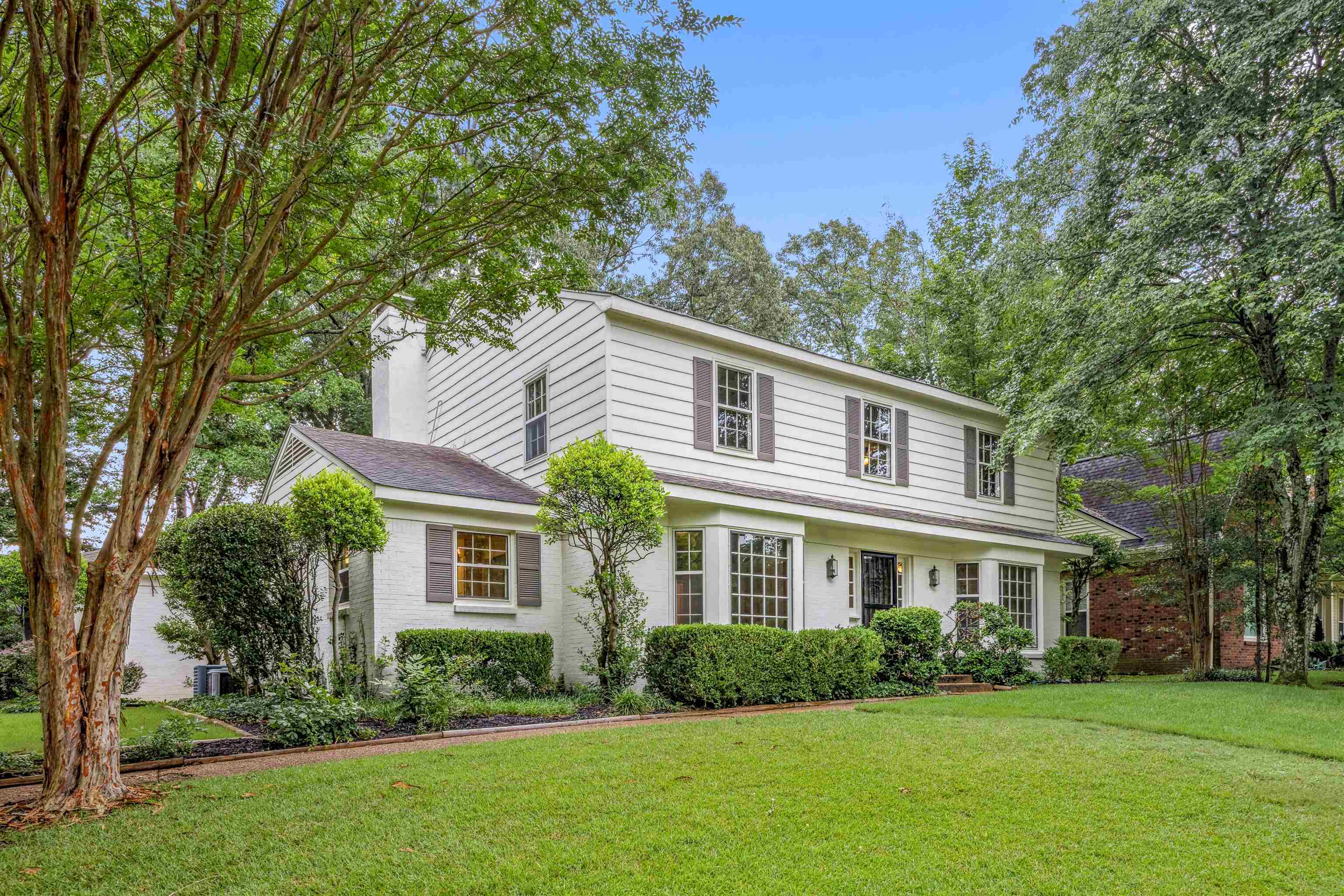 View of front of home with a front lawn, brick siding, and a shingled roof