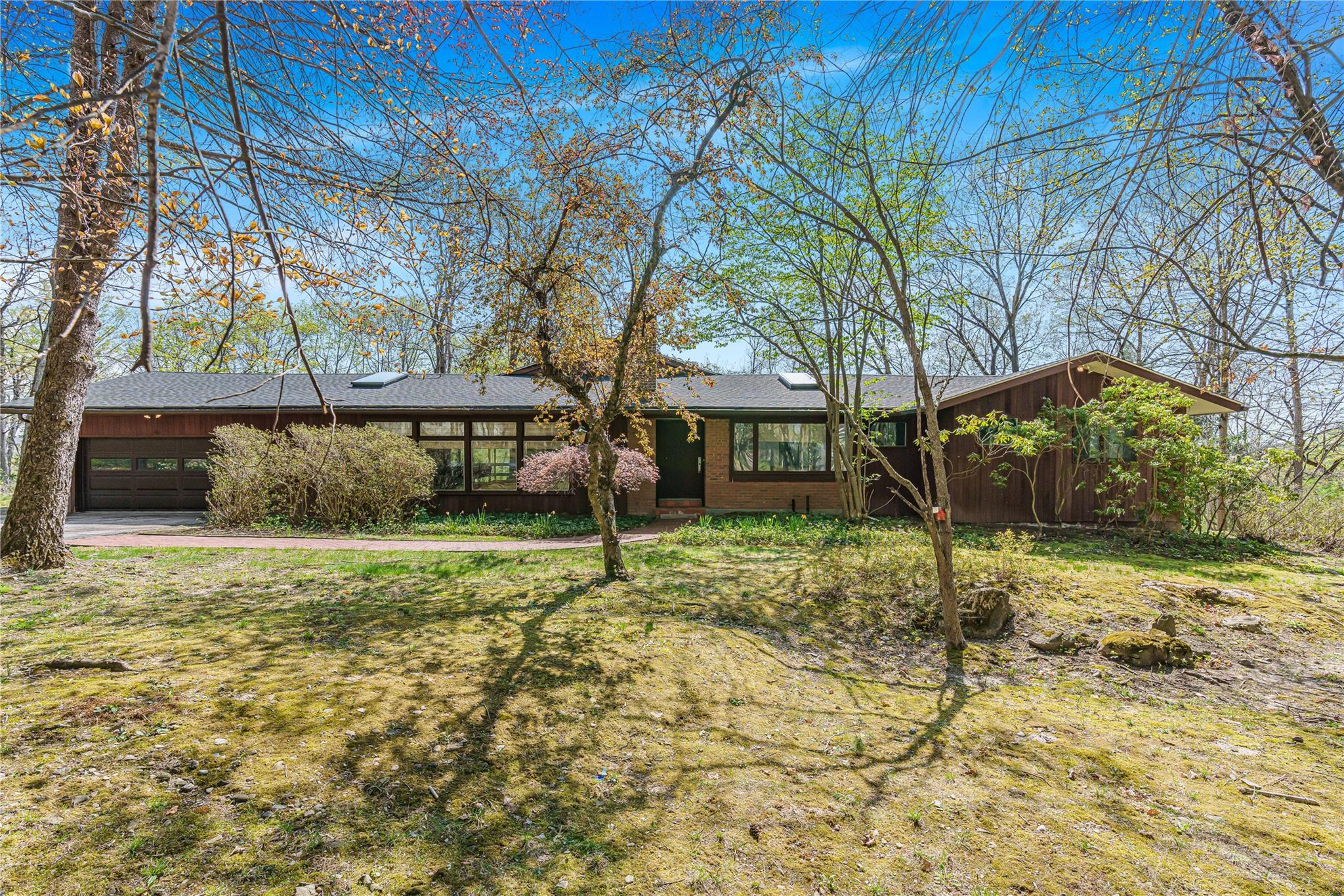 View of front of home with a garage, concrete driveway, board and batten siding, and brick siding