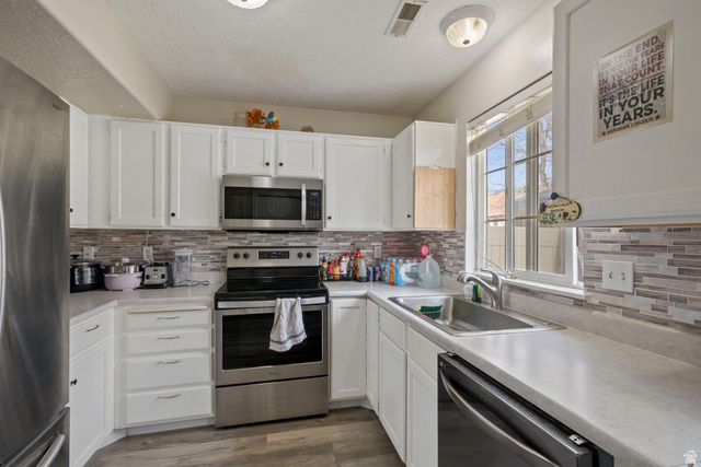 962 Independence Avenue Provo, UT 84604 - Photo 6 of 31 Kitchen featuring stainless steel appliances, light countertops, white cabinetry, a textured ceiling, and dark wood-style flooring