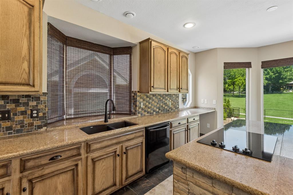 2925 Sunset Ridge McKinney, TX 75072 - Photo 14 of 33 Another view of this beautifully designed chef’s kitchen featuring a large center island, abundant cabinetry, granite surfaces, and an open layout filled with natural light and scenic golf course views.