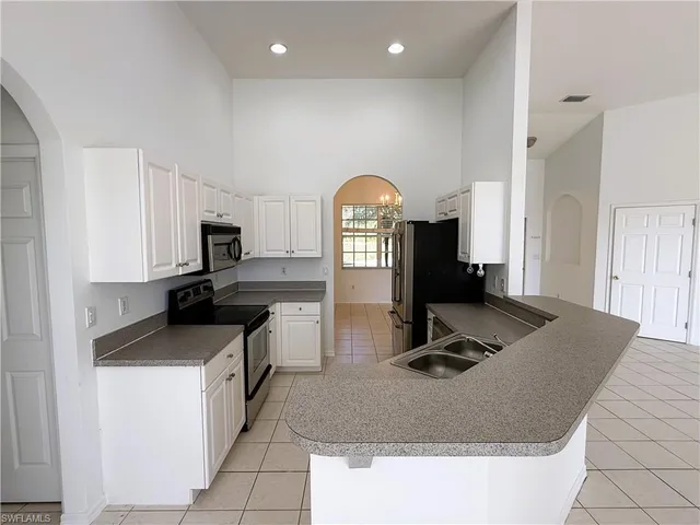 a kitchen with kitchen island granite countertop a sink a stove and cabinets