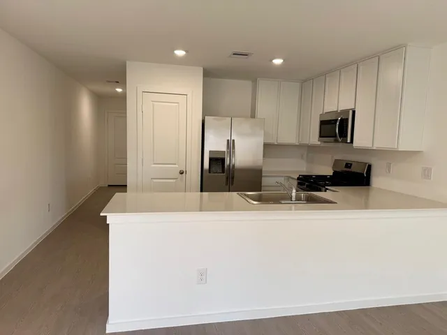 a large kitchen with stainless steel appliances granite countertop a refrigerator a sink a stove a microwave and white cabinets