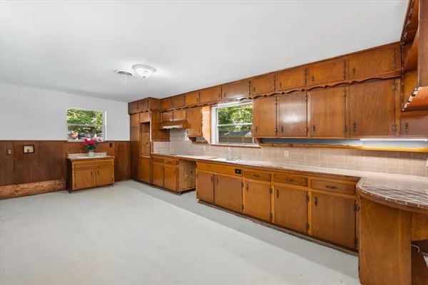 a large kitchen with stainless steel appliances wooden cabinets and a counter top space