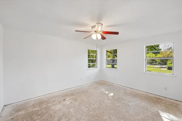 an empty room with windows and fan