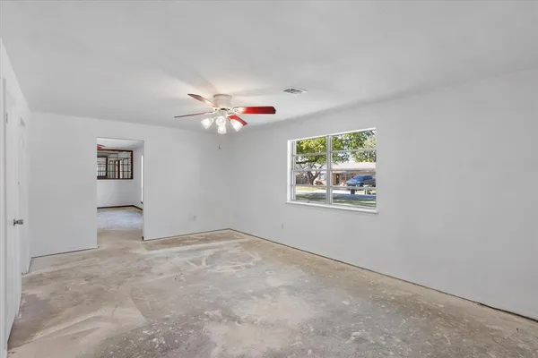 an empty room with windows and fan