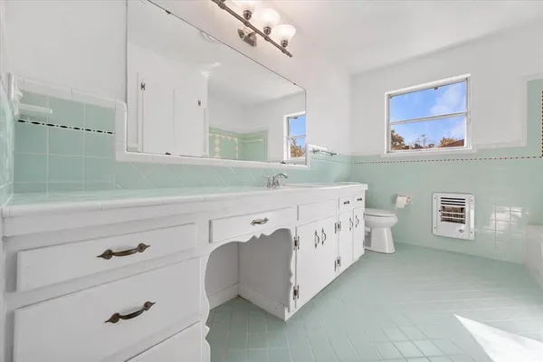 a spacious bathroom with a double vanity sink a mirror a bathtub and a window