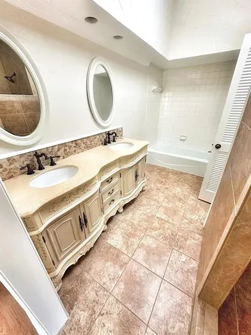 a bathroom with a double vanity sink mirror and bathtub