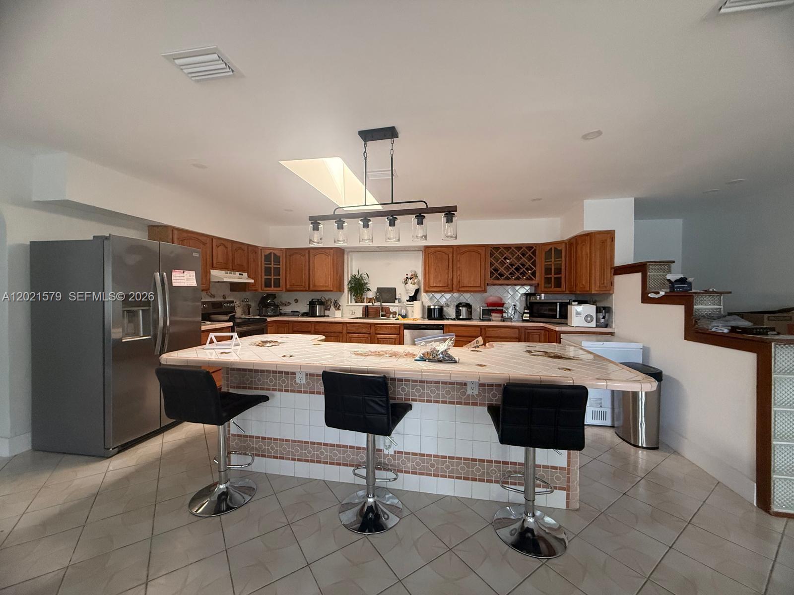 22445 Southwest 264th Street Homestead, FL 33031 - Photo 4 of 12 a view of kitchen with kitchen island stainless steel appliances refrigerator stove dining table and chairs