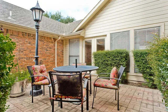 a patio with table and chairs and potted plants