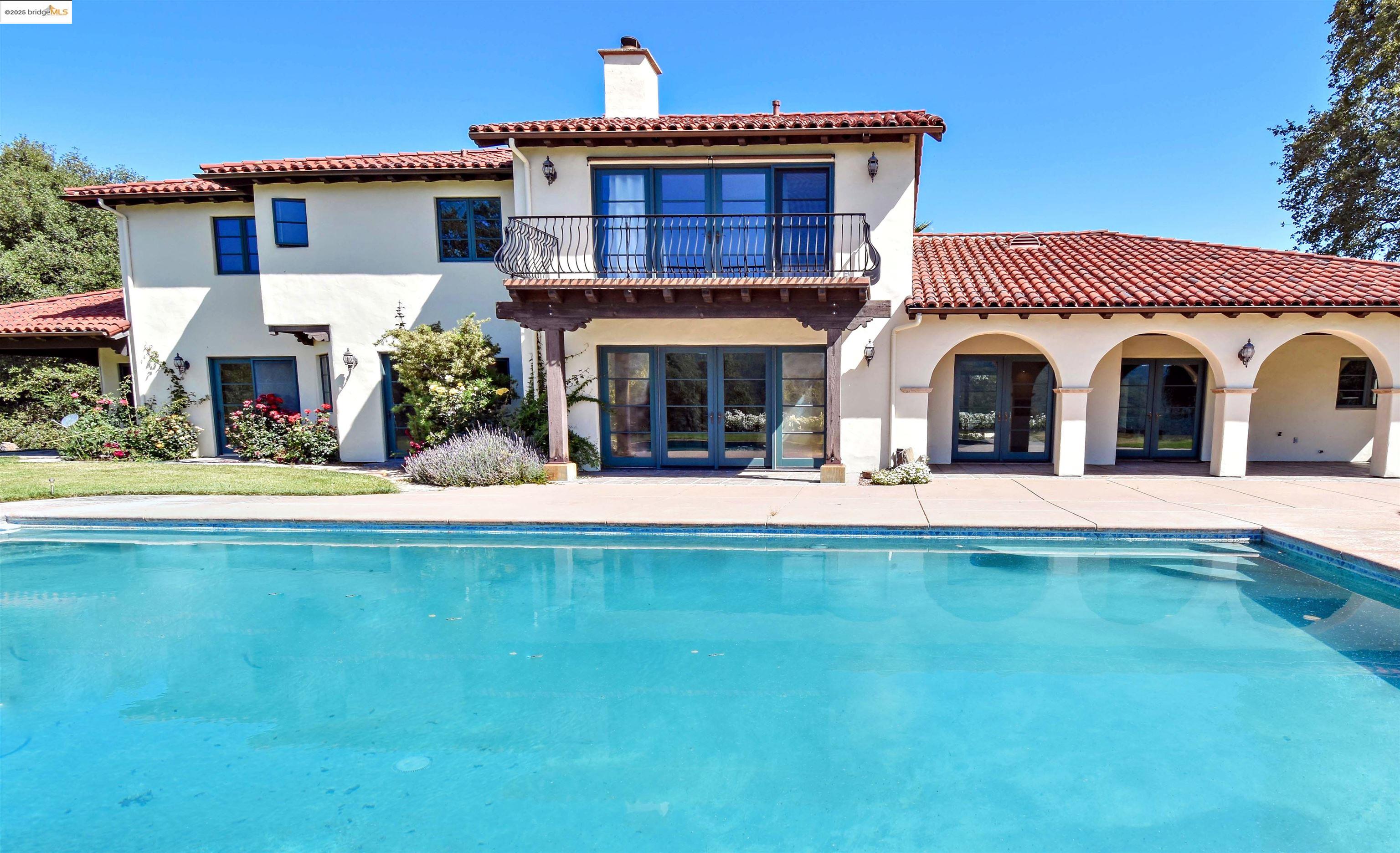 26255 Powell Ranch Road Sonora, CA 95370 - Photo 32 of 48 a view of a white house with a large pool and a yard table and chairs