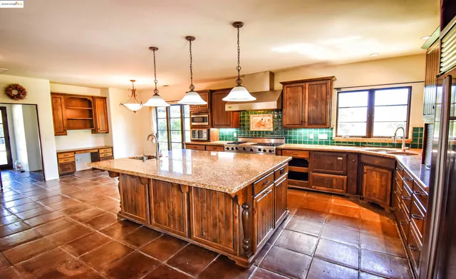 a kitchen with stainless steel appliances granite countertop a kitchen island a stove a sink a oven and a center island