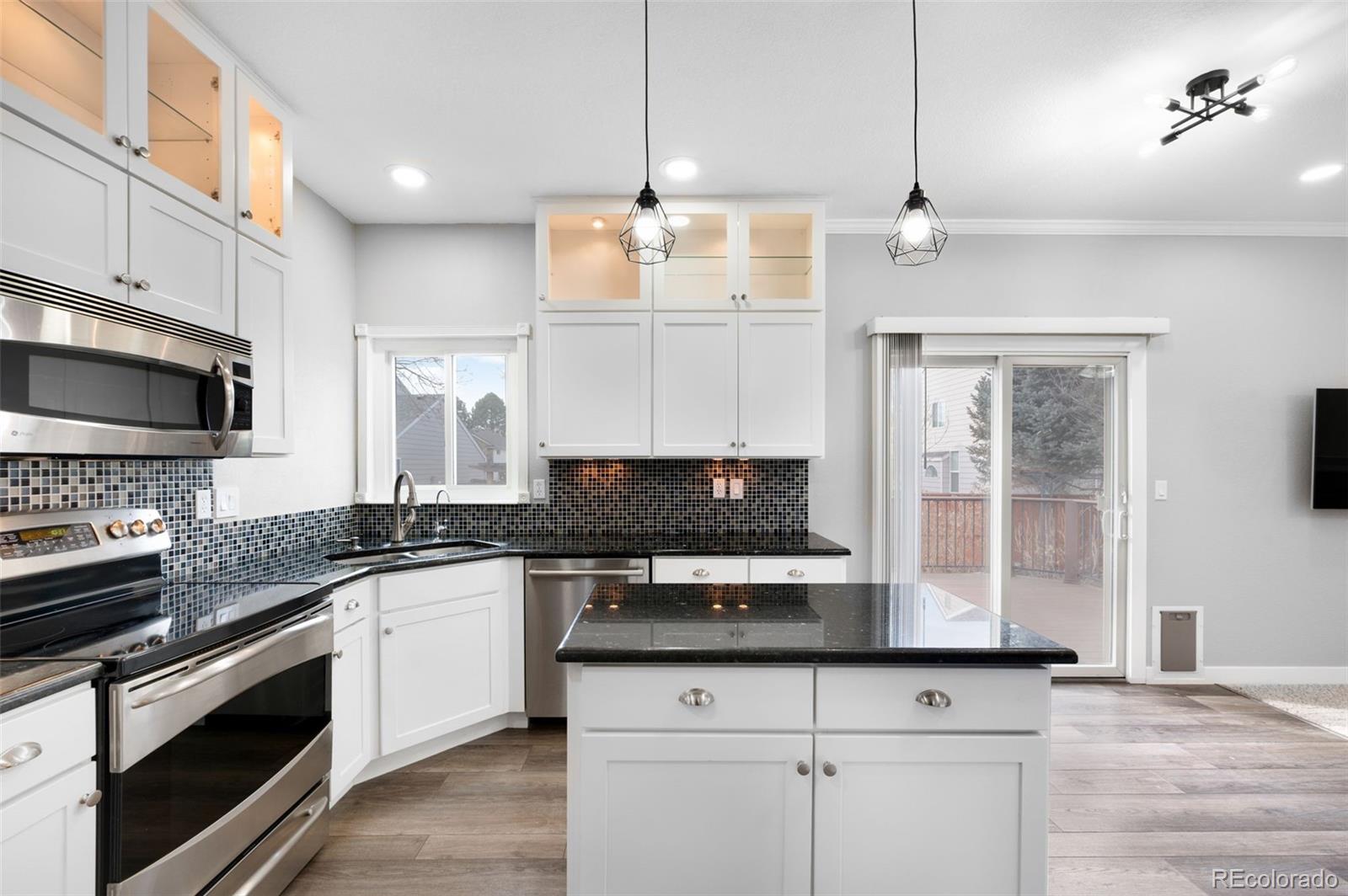 3618 West Rosewalk Circle Highlands Ranch, CO 80129 - Photo 2 of 45 a kitchen with stainless steel appliances granite countertop a stove a sink and a microwave