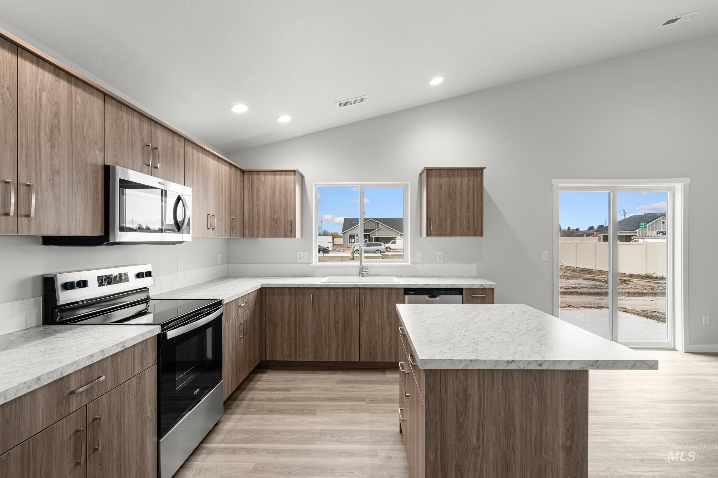 511 Hamlow Avenue Middleton, ID 83644 - Photo 6 of 22 Kitchen with stainless steel appliances, light countertops, light wood finished floors, a center island, and lofted ceiling