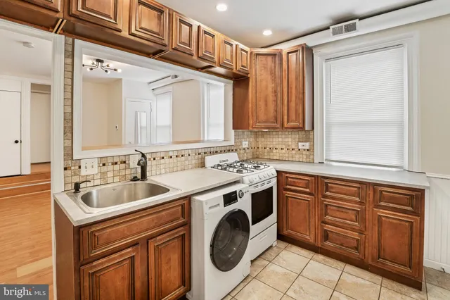 a utility room with stainless steel appliances granite countertop a sink and dishwasher next to a window