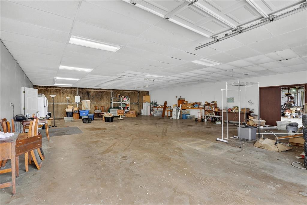 1092 West Highway 199 Springtown, TX 76082 - Photo 24 of 29 Expansive garage space featuring a concrete floor, drop ceiling with fluorescent lighting, and two overhead garage door