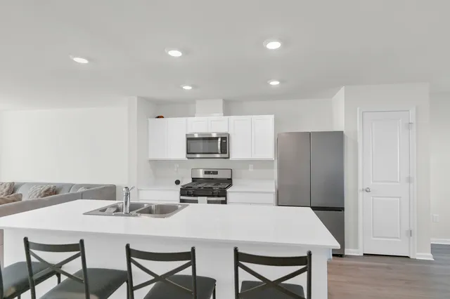 a kitchen with stainless steel appliances a table and chairs in it