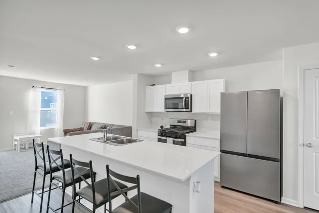 a kitchen that has a refrigerator a table and chairs in it