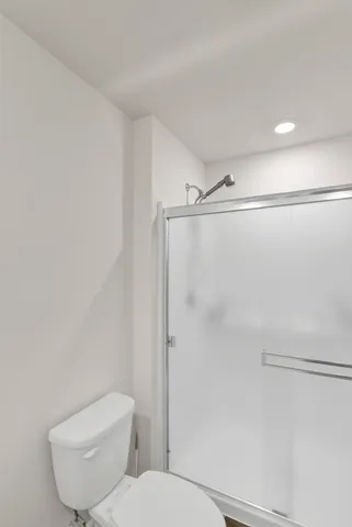 a white toilet sitting next to a shower