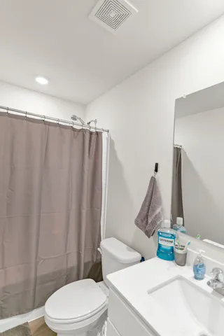 a white toilet sitting next to a bathroom sink and a shower