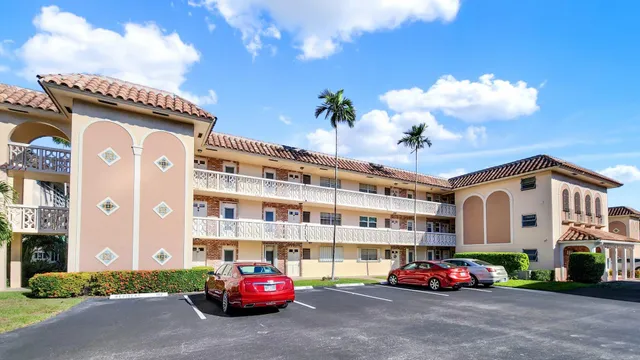 a front view of a house with a yard and palm trees