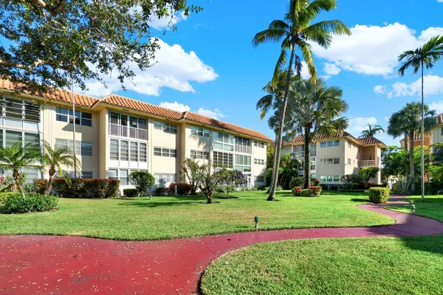 a front view of a house with a yard and palm trees