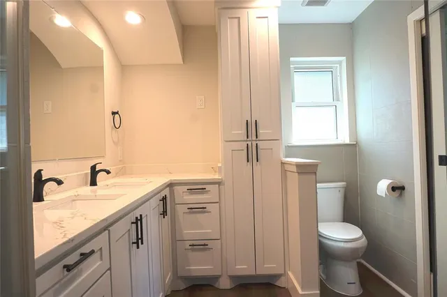 a bathroom with a toilet a sink a vanity and mirror