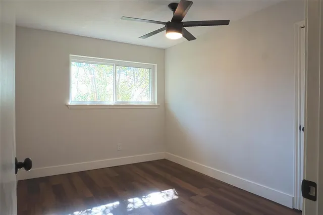 an empty room with wooden floor closet and windows