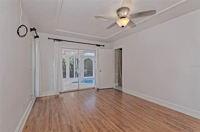 a view of empty room with wooden floor and fan