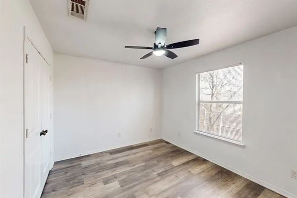 a view of empty room with wooden floor and fan