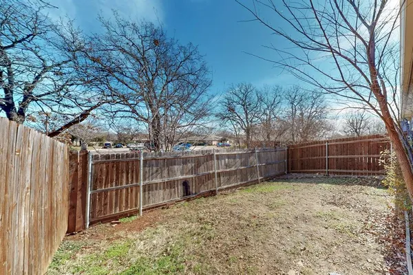 a view of a backyard with wooden fence and large trees