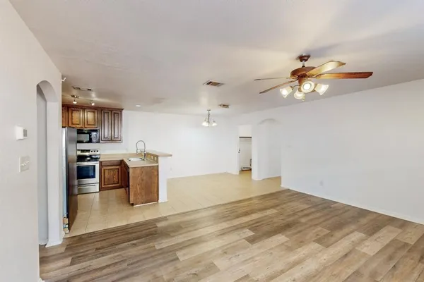 a view of a kitchen with a stove cabinets a ceiling fan and wooden floor