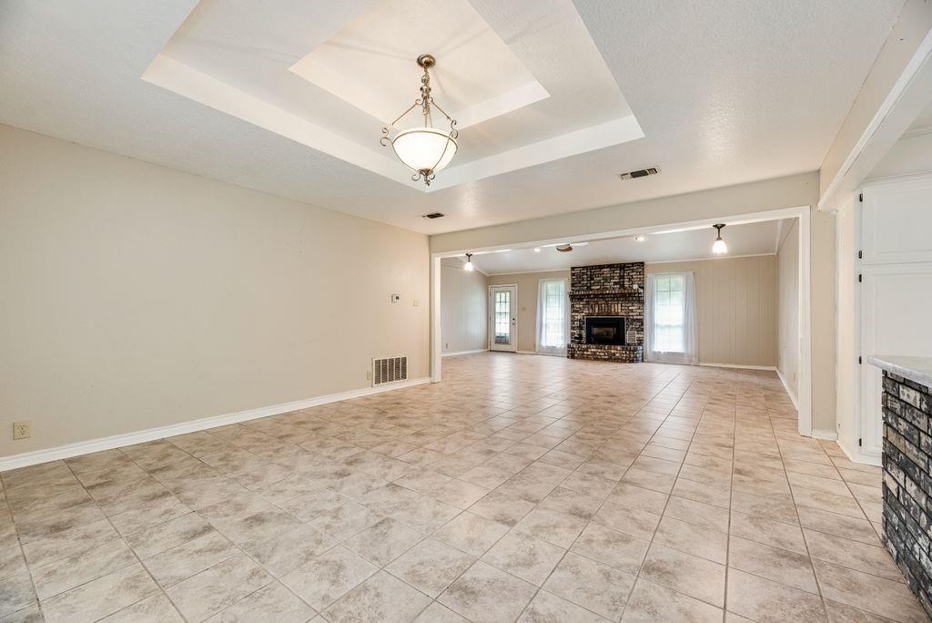298 Butterfield Road Denison, TX 75021 - Photo 22 of 34 Expansive tiled flooring spans the open concept room, featuring a tray ceiling with a central chandelier