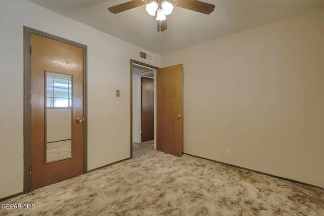 an empty room with a window and ceiling fan