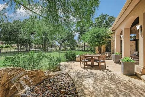 a view of a patio with table and chairs potted plants and a large tree