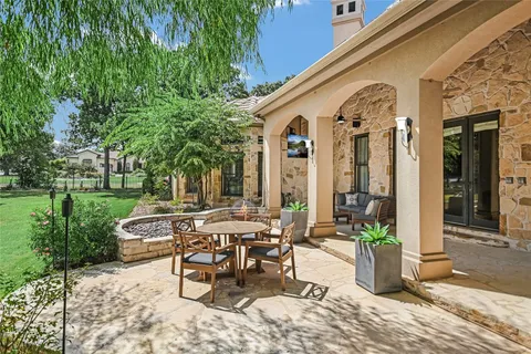 a view of a patio with table and chairs potted plants and large tree